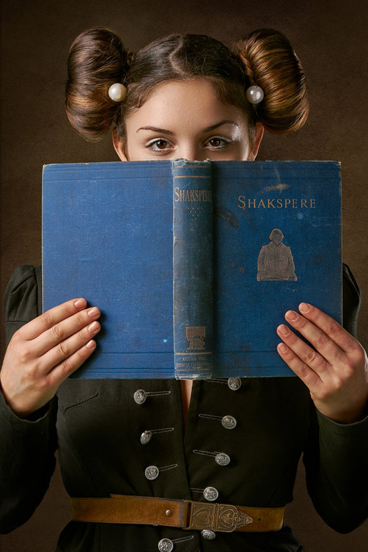 A young girl proudly holds up a well-worn book of Shakespeare's works, her eyes sparkling with enthusiasm as she shares her passion for the timeless literature.