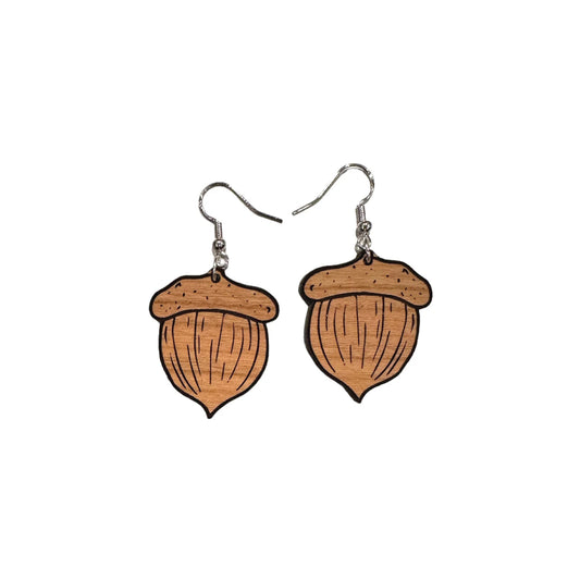 May include: A pair of brown wooden acorn dangle earrings. Each earring features a detailed acorn design with visible wood grain texture and black outlines. The earrings hang from silver-toned hooks. These nature-inspired earrings are perfect for adding a touch of autumn charm to any outfit.