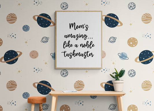 May include: A framed print with the text &#39;Mom&#39;s amazing... like a noble taskmaster&#39; on a white background. The print is hanging on a wall with a light beige background. The wall is decorated with a repeating pattern of blue and brown planets and stars.