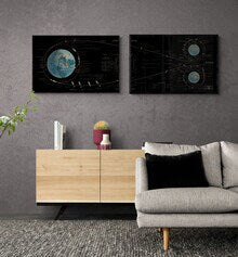 May include: Two black and white abstract art prints with a celestial theme. The prints feature a circular design with a blue and white planet in the center, surrounded by stars and lines. The prints are displayed on a gray wall above a wooden cabinet and a gray sofa.