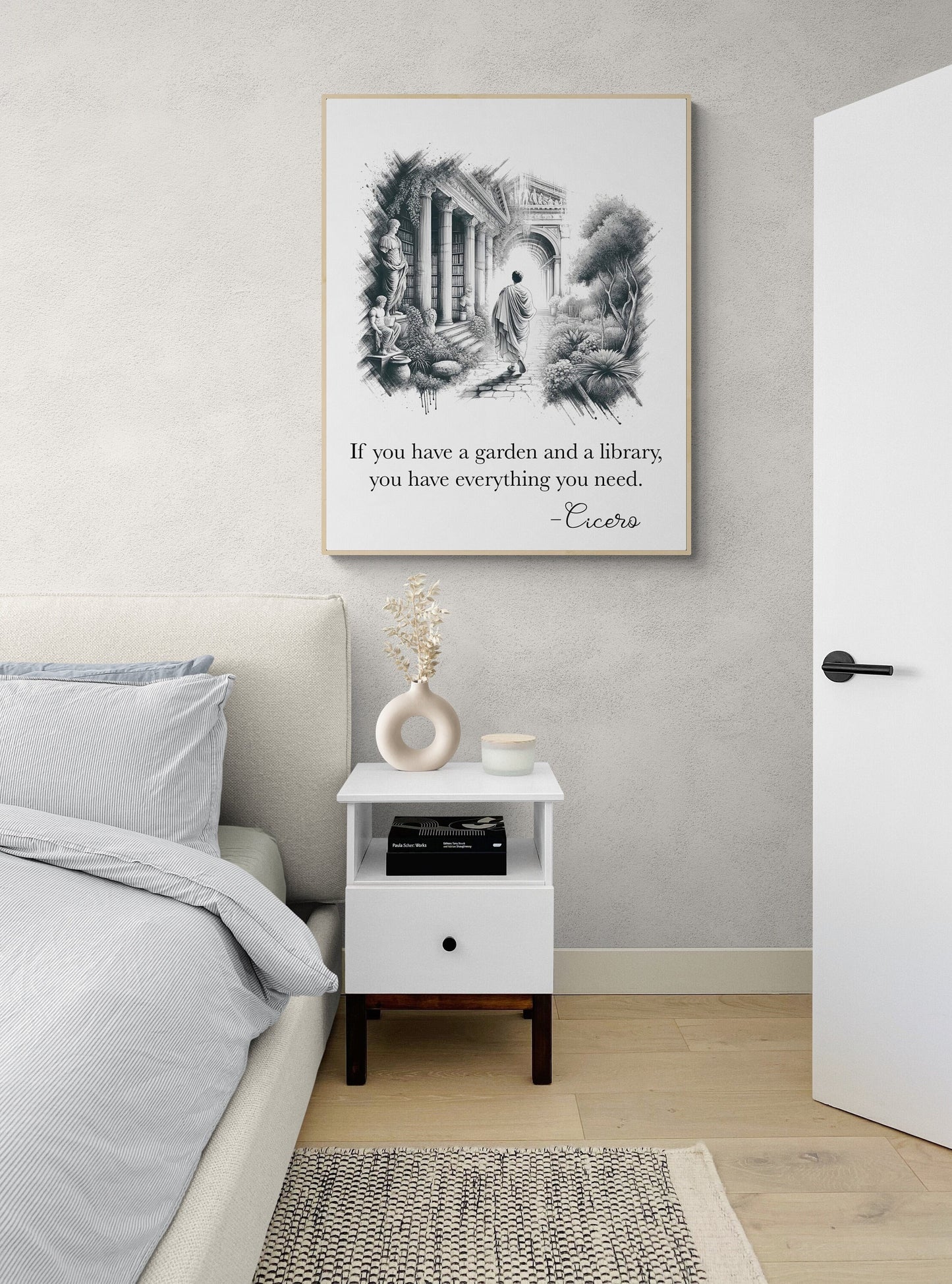 May include: A white nightstand with a drawer and a shelf. The nightstand has a black knob on the drawer. A book is on the shelf. A white vase with dried flowers is on the top shelf. The nightstand is next to a bed with a white and gray striped pillow and a white comforter. A black and white framed print with a quote by Cicero is on the wall behind the nightstand. The quote reads: 'If you have a garden and a library, you have everything you need. -Cicero'.