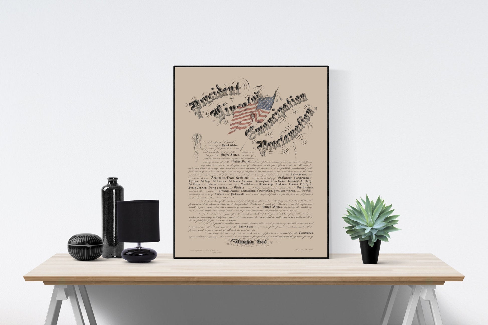 May include: A framed print of the Emancipation Proclamation document with a stylized American flag in the upper left corner. The document is printed on a tan background with black text. The text reads 'President of the United States of America Proclamation' and includes the names of the states that were in rebellion. The document is signed 'Abraham Lincoln' and dated 'January 1, 1863'. The document is framed in a black frame.