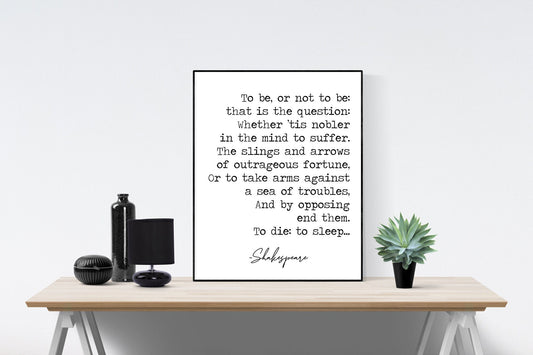 May include: A black and white framed print of a Shakespeare quote on a wooden table. The quote reads: 'To be, or not to be: that is the question: Whether 'tis nobler in the mind to suffer. The slings and arrows of outrageous fortune, Or to take arms against a sea of troubles, And by opposing end them. To die: to sleep... Shakespeare'.