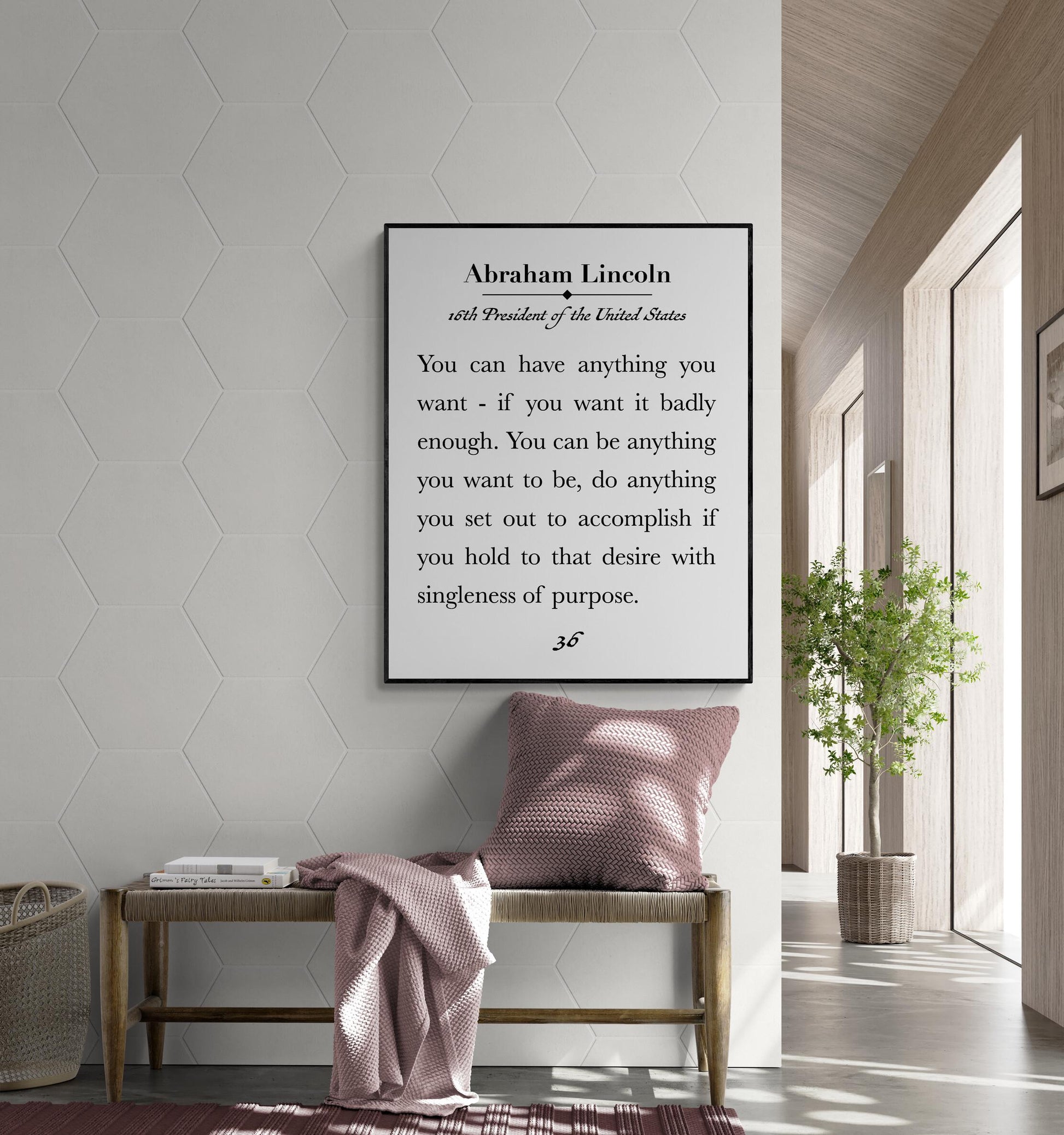 May include: A framed print featuring a quote by Abraham Lincoln, 16th President of the United States. The quote is in a black frame and is displayed above a wooden bench with a pink pillow and blanket. The wall is white with a hexagonal pattern. A potted plant is in the background.