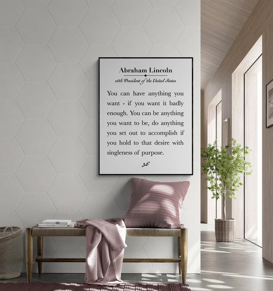 May include: A framed print featuring a quote by Abraham Lincoln, 16th President of the United States. The quote is in a black frame and is displayed above a wooden bench with a pink pillow and blanket. The wall is white with a hexagonal pattern. A potted plant is in the background.