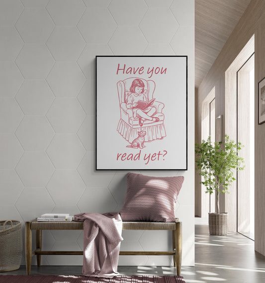 May include: A framed print with a pink illustration of a girl reading in a chair with a dog. The text on the print reads 'Have you read yet?'. The print is displayed above a wooden bench with a pink pillow and blanket. The wall has a hexagonal pattern.